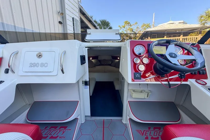 Slide: The Image of 2022 Velocity 290SC boat interior with red and white dashboard, steering wheel, and cabin entrance. - 40