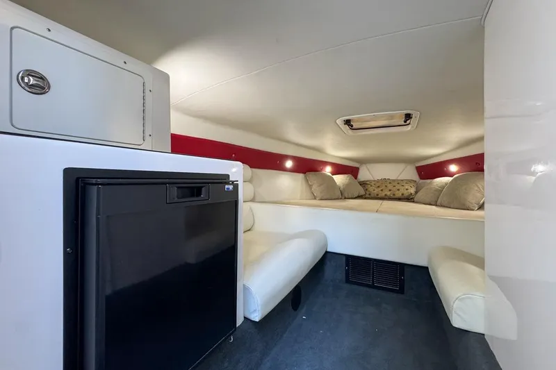 Slide: The Image of 2022 Velocity 290sc boat interior with cozy seating, fridge, and ambient lighting. - 54