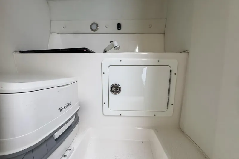 Slide: The Image of 2022 Velocity 290sc boat interior with compact toilet and storage compartment. - 76