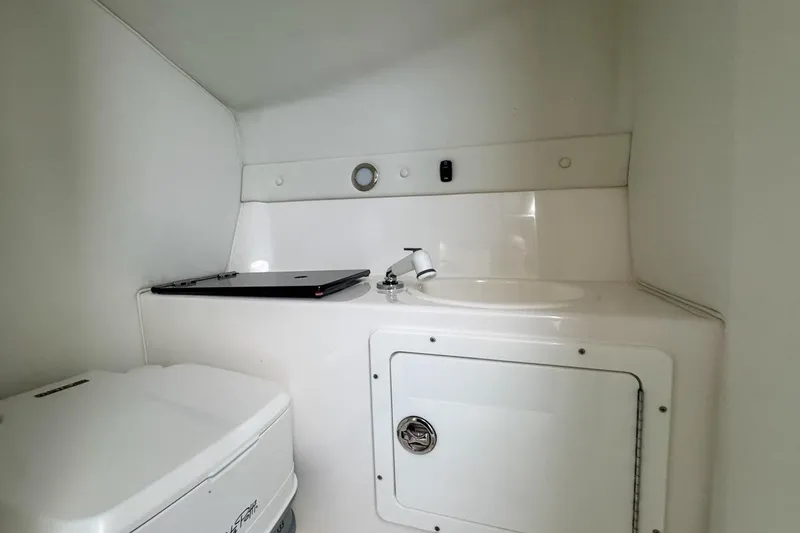 Slide: The Image of 2022 Velocity 290sc boat interior with compact bathroom and sink area. - 77