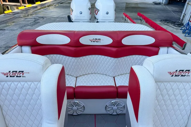 Slide: The Image of 2022 Velocity 290sc boat interior with red and white seating, docked with twin engines. - 93