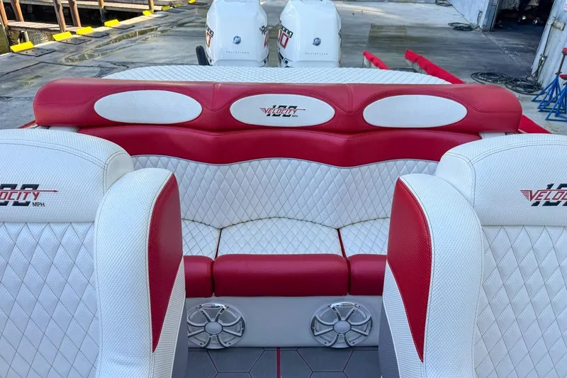 Slide: The Image of 2022 Velocity 290sc boat interior with red and white seating, dockside view. - 94