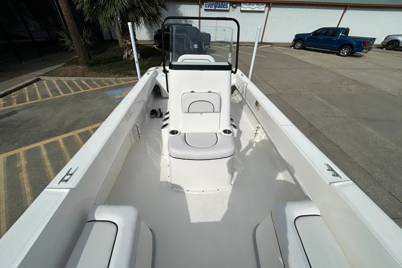 Slide: The Image of 2026 Sundance B20CCR boat interior with seating and console, parked outdoors. - 9