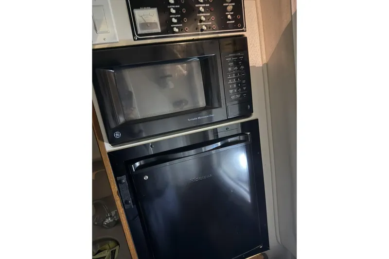 Slide: The Image of Microwave and mini fridge in 2000 Pursuit 3070 Offshore Center Console boat kitchen. - 19