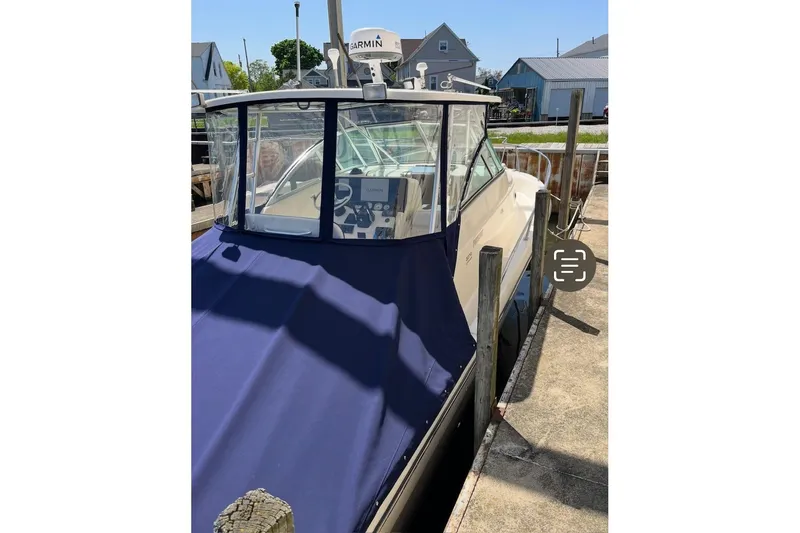 Slide: The Image of 2000 Pursuit 3070 Offshore Center Console boat docked with blue cover. - 4