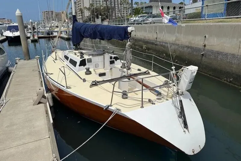 The Image of 1983 Nelson Marek 36 sailboat docked at marina, featuring sleek wooden hull and blue sail cover. - 0