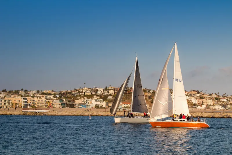 Slide: The Image of Sailboats on the water near a coastal town, featuring a 1983 Nelson Marek 36. - 2