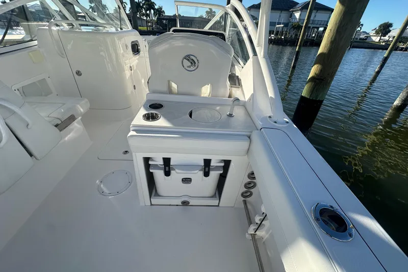 Slide: The Image of 2023 Edgewater 248CX Crossover boat interior with seating and storage, docked by the water. - 10