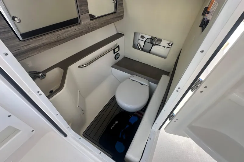 Slide: The Image of 2023 Edgewater 248CX Crossover boat interior with compact marine toilet and storage. - 17