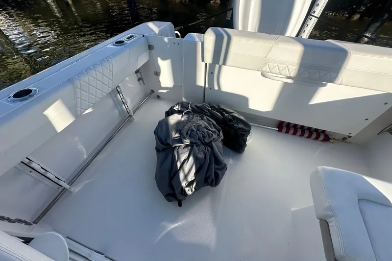 Slide: The Image of 2023 Edgewater 248CX Crossover boat interior with white seating and folded cover. - 19