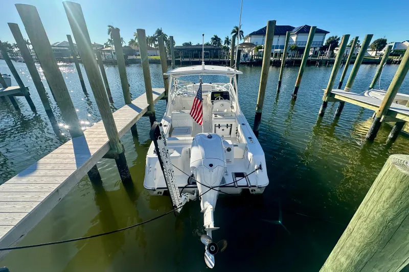 Slide: The Image of 2023 Edgewater 248CX Crossover boat docked in sunny marina setting. - 2