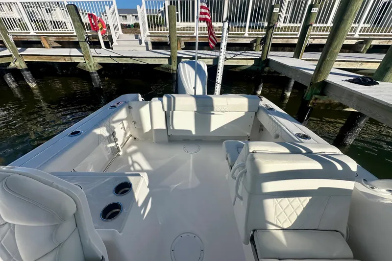 Slide: The Image of 2023 Edgewater 248CX Crossover boat interior with seating and cup holders at a dock. - 3