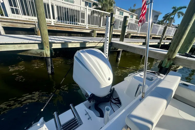 Slide: The Image of 2023 Edgewater 248CX Crossover boat docked, featuring outboard motor and American flag. - 6