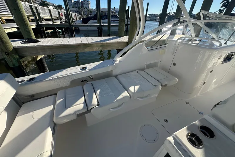 Slide: The Image of 2023 Edgewater 248CX Crossover boat interior with white seating and dock view. - 9