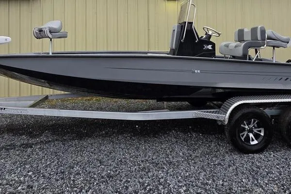 Slide: The Image of 2025 Xpress H22B Bay boat on trailer, gray exterior, parked on gravel. - 7