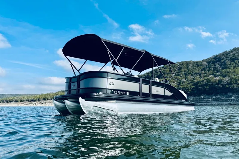 Slide: The Image of 2019 Barletta L23UC pontoon boat on a scenic lake with hills in the background. - 2