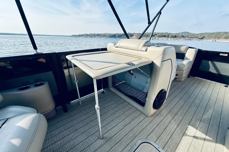 Slide: The Image of Luxurious 2019 Barletta L23UC pontoon boat interior with seating and table on a serene lake. - 27