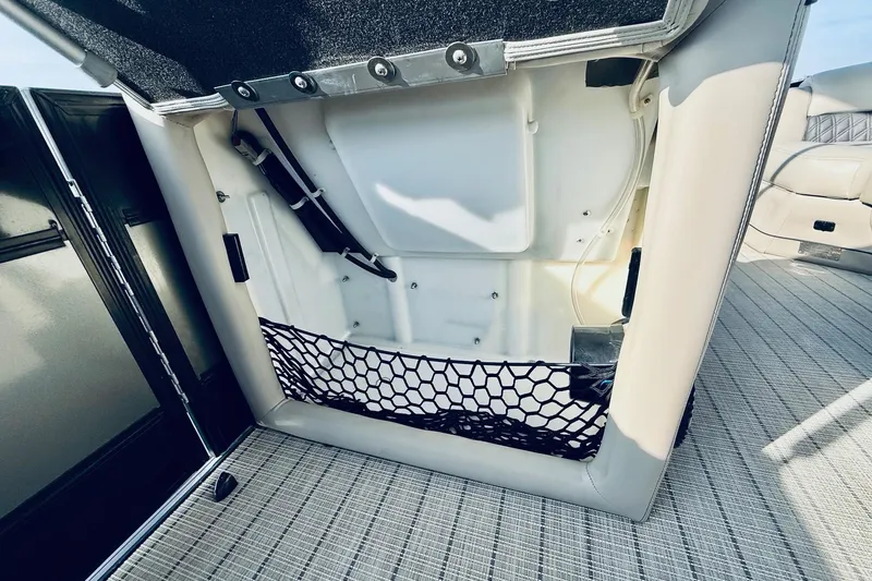 Slide: The Image of Interior storage compartment of a 2019 Barletta L23UC boat with netting and upholstery. - 28