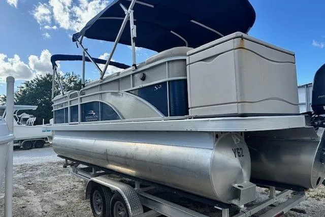 Slide: The Image of 2015 Bennington 21gs pontoon boat on trailer, parked outdoors under cloudy sky. - 3