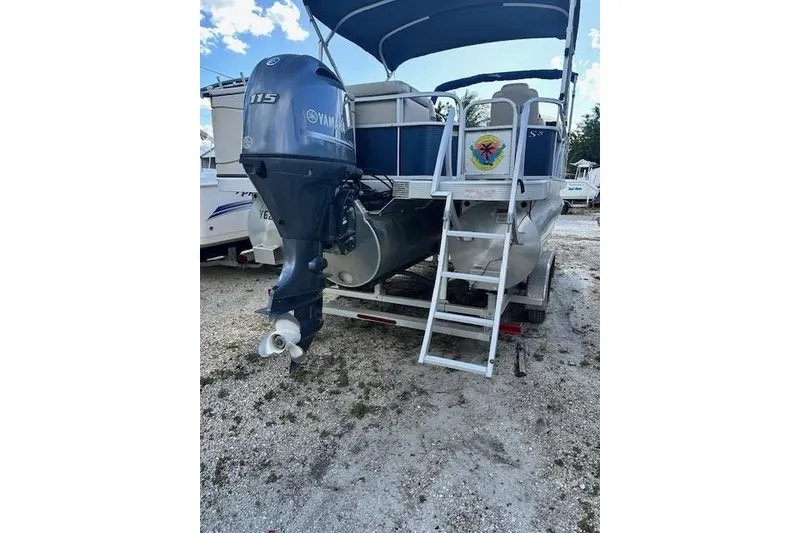 Slide: The Image of 2015 Bennington 21gs pontoon boat on trailer, parked outdoors under blue sky. - 4