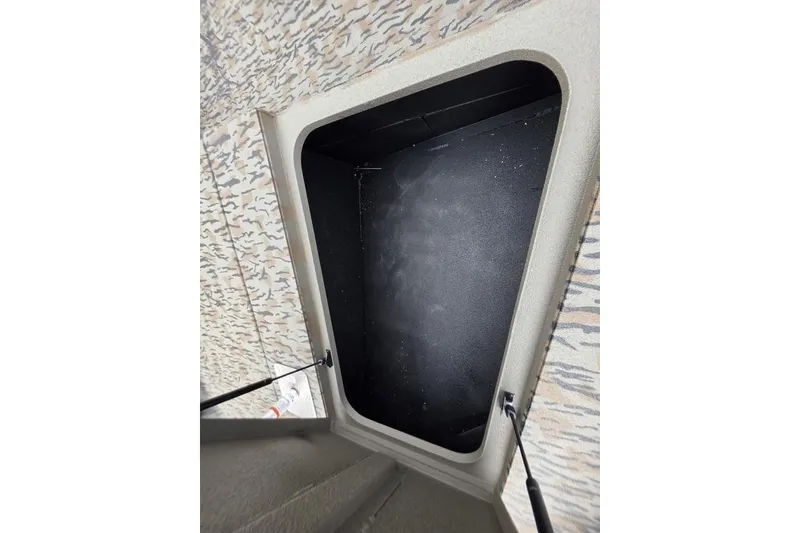 Slide: The Image of Open storage compartment in 2026 Xpress H190B Bay boat, featuring camo-patterned interior. - 17