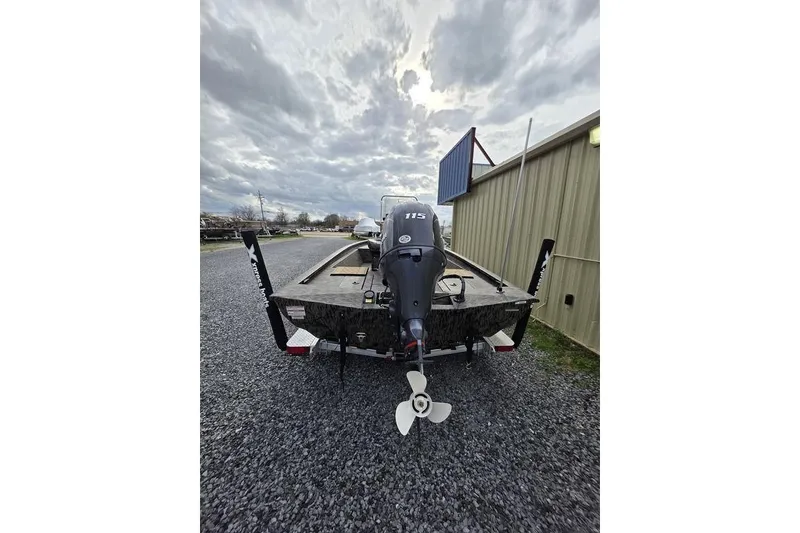 Slide: The Image of 2026 Xpress H190B Bay boat with outboard motor, parked on gravel near a building. - 3