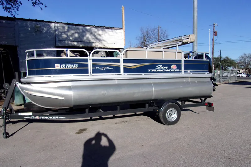 The Image of 2023 Sun Tracker Bass Buggy 18 DLX pontoon boat on trailer, parked outdoors. - 1