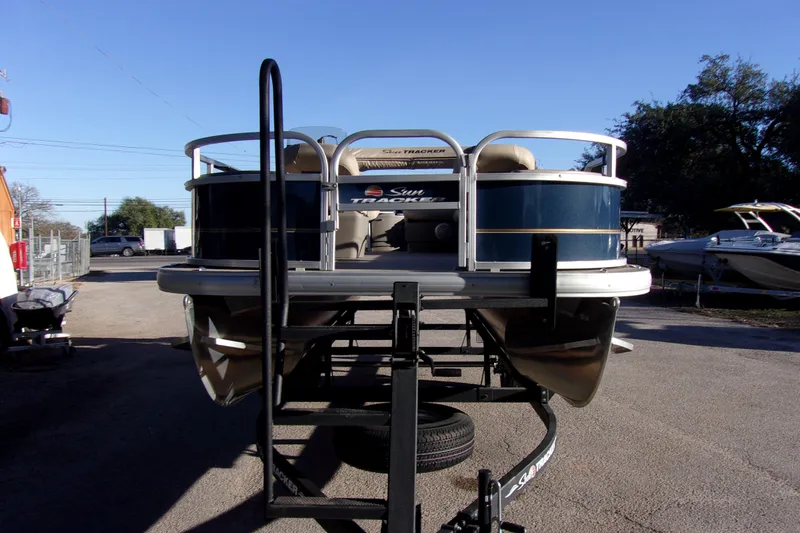 Slide: The Image of 2023 Sun Tracker Bass Buggy 18 DLX pontoon boat on trailer, parked outdoors. - 4