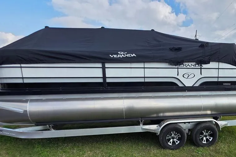 Slide: The Image of 2026 Veranda Vista Sport 22RC Tri-Toon boat with cover on trailer, outdoors. - 4