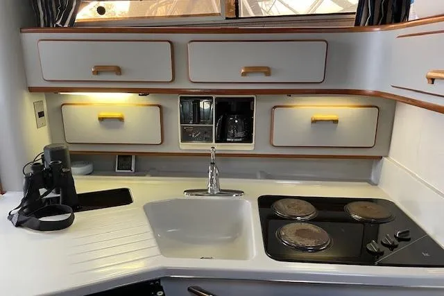 Slide: The Image of 1990 Sea Ray Sundancer 350 cabin interior with seating, table, and striped curtain. - 13