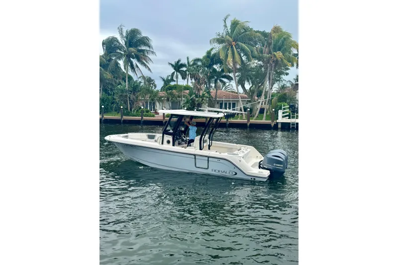 The Image of 2022 Robalo R272 Center Console boat on water, surrounded by palm trees. - 0