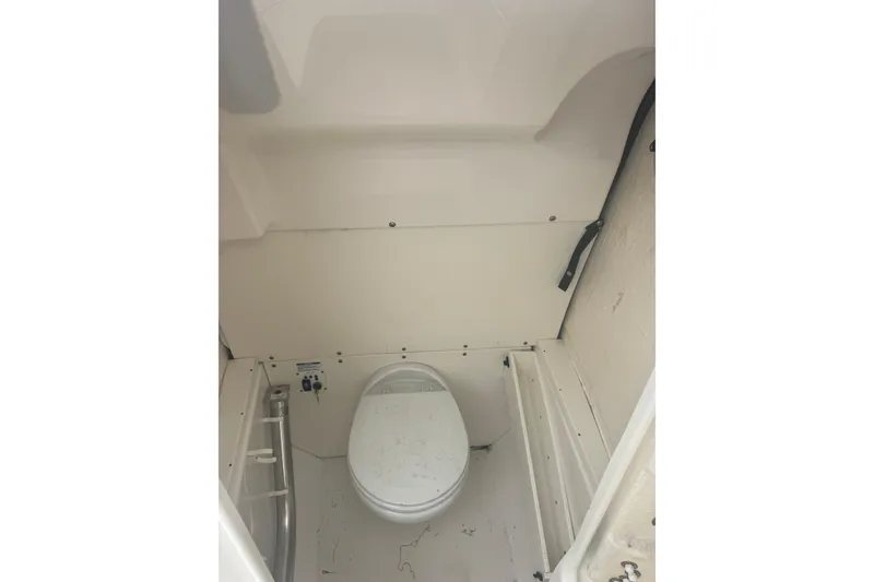 Slide: The Image of 2022 Robalo R272 Center Console boat interior with a compact marine toilet. - 12