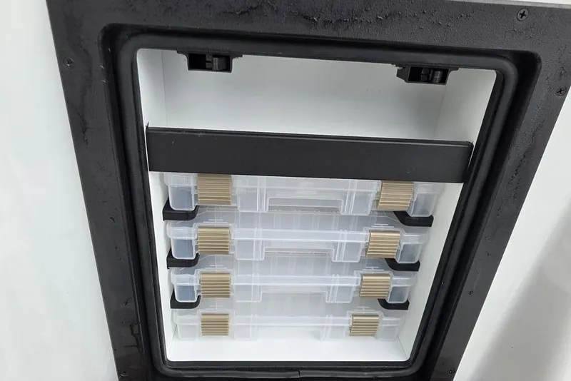 Slide: The Image of Storage compartment with clear plastic boxes in a 2026 Xpress H20B Bay boat. - 32