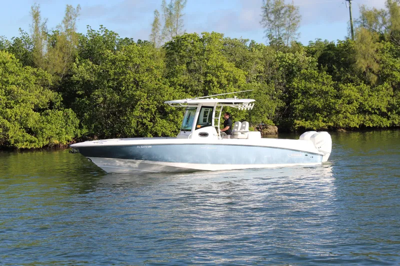 Slide: The Image of 2015 Boston Whaler 320 Outrage boat cruising on a calm river near lush greenery. - 20