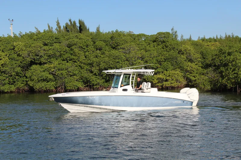 Slide: The Image of 2015 Boston Whaler 320 Outrage boat cruising on calm water near lush greenery. - 21