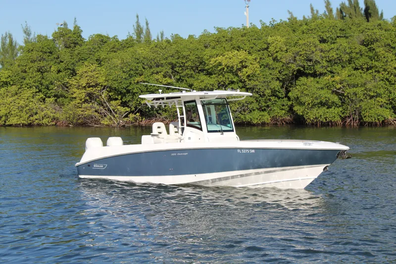 Slide: The Image of 2015 Boston Whaler 320 Outrage boat on calm water near lush greenery. - 23