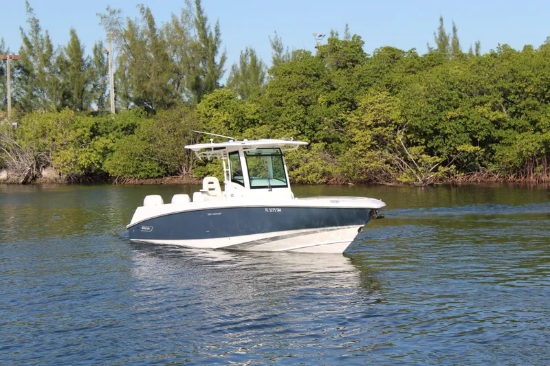 Slide: The Image of 2015 Boston Whaler 320 Outrage boat on calm water near lush greenery. - 31