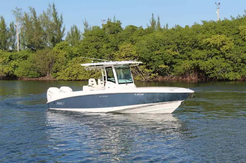 Slide: The Image of 2015 Boston Whaler 320 Outrage boat cruising on calm water near lush greenery. - 32