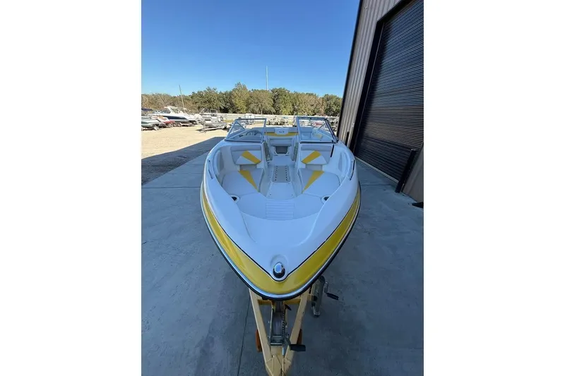 Slide: The Image of 2008 Glastron GX 205 boat with yellow accents, parked outside a storage facility. - 1