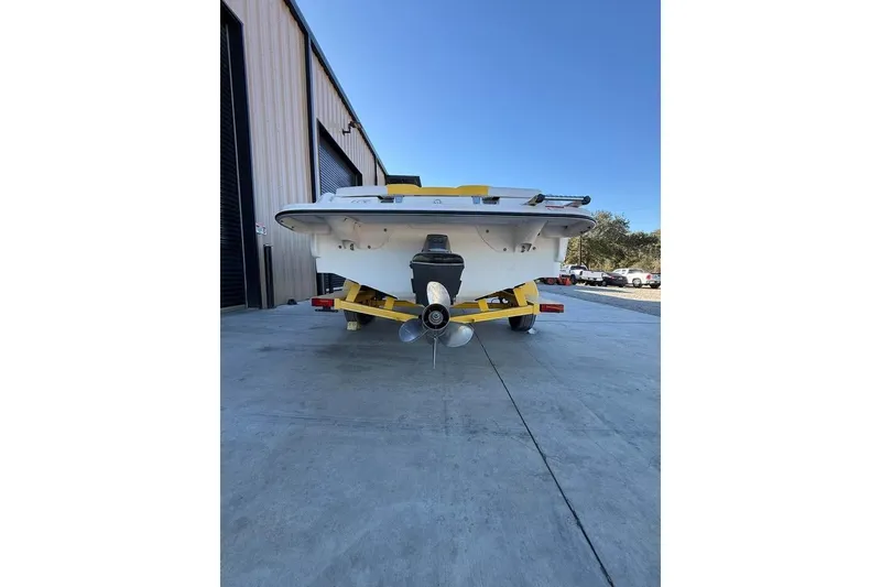 Slide: The Image of 2008 Glastron GX 205 boat on yellow trailer, parked outside a warehouse. - 2