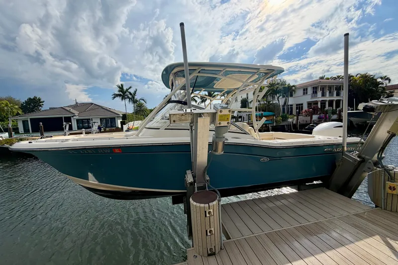 The Image of 2019 Grady-White Freedom 235 boat docked by waterfront homes under a cloudy sky. - 0