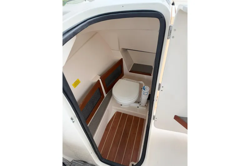 Slide: The Image of 2019 Grady-White Freedom 235 boat interior with compact marine toilet and wooden flooring. - 11