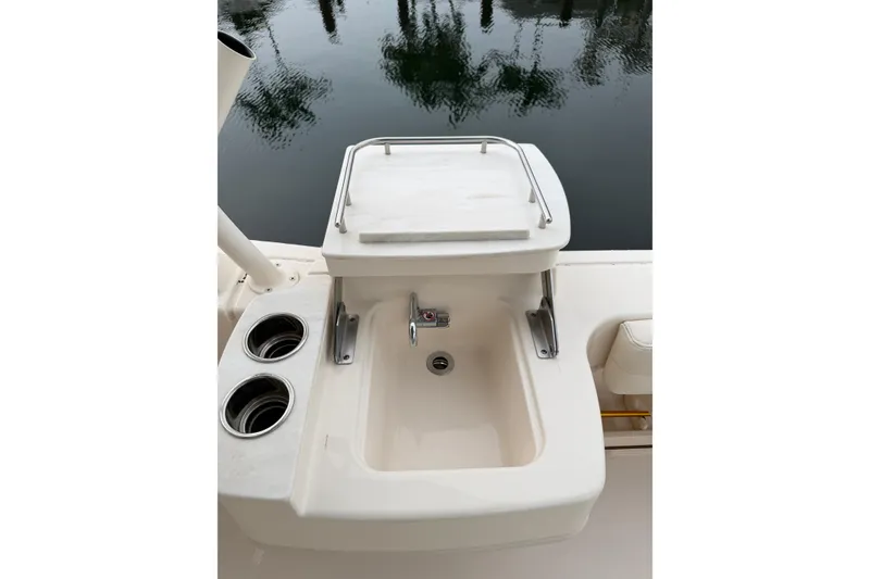 Slide: The Image of 2019 Grady-White Freedom 235 boat sink with cup holders, docked by calm water. - 13