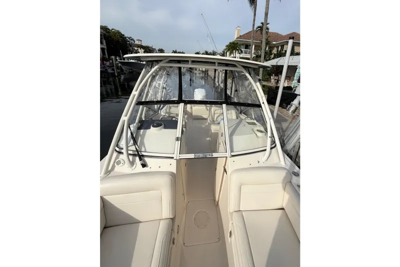 Slide: The Image of 2019 Grady-White Freedom 235 boat interior with seating and windshield, docked by waterfront homes. - 8