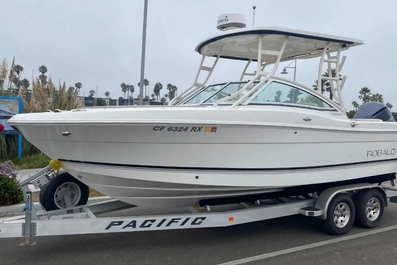 Slide: The Image of 2017 Robalo R247 Dual Console boat on trailer, parked outdoors. - 2
