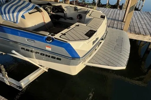 Slide: The Image of 2017 Malibu Response TXi Open Bow boat docked, featuring sleek design and blue accents. - 5