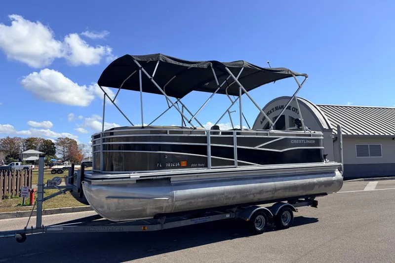 Slide: The Image of 2019 Crestliner 200 Rally CS pontoon boat on trailer, parked outdoors. - 1