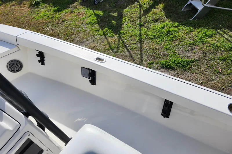 Slide: The Image of 2022 Pathfinder 2400 TRS boat interior, featuring white seating and speaker, on grassy background. - 20