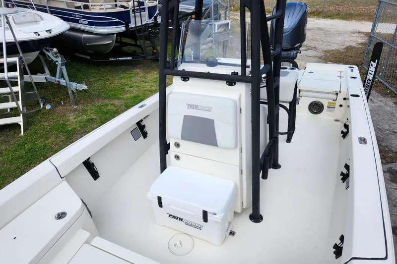 Slide: The Image of 2022 Pathfinder 2400 TRS boat interior with seating and storage, docked outdoors. - 44
