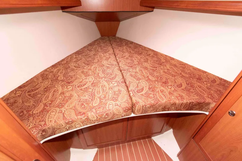 Slide: The Image of 2009 Hunter 36 sailboat cabin with paisley-patterned bedding and wooden interior. - 12